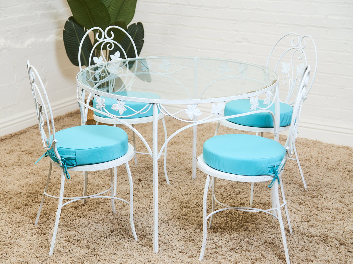 Vintage Wrought Iron Patio Dining Table with Leaf Motif Aqua Cushions and Glass Top